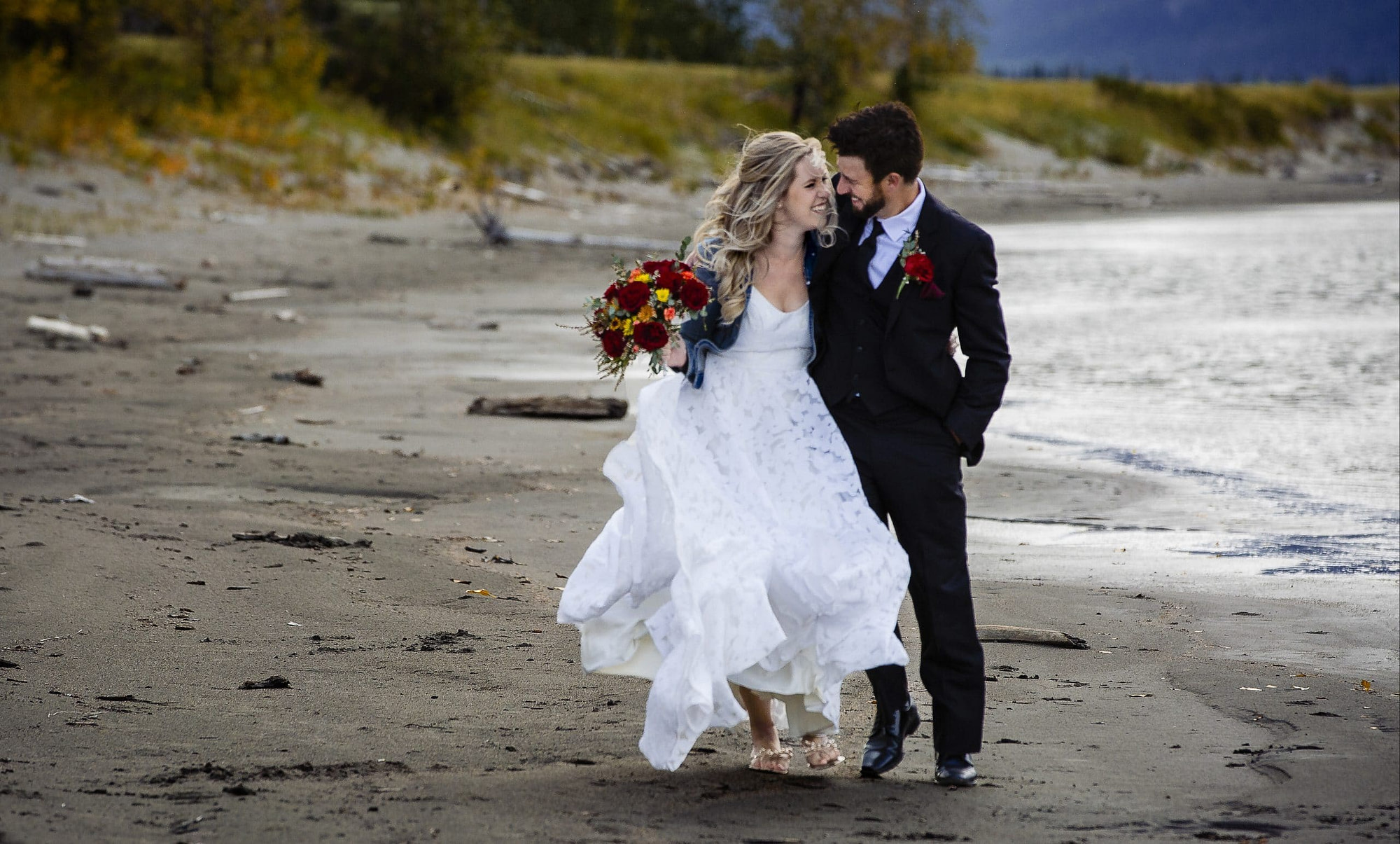 couple walking and laughing as they walk along Jasper Lake beach|Jasper Photographer