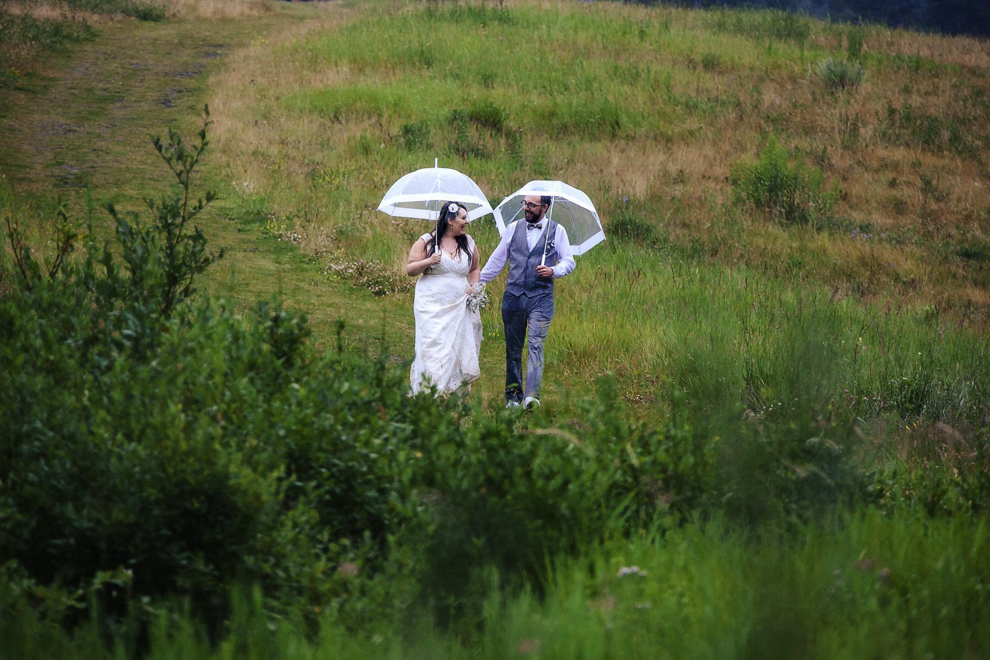 wedding couple walking in the rain with umbrellas get great wedding photos even in the rain