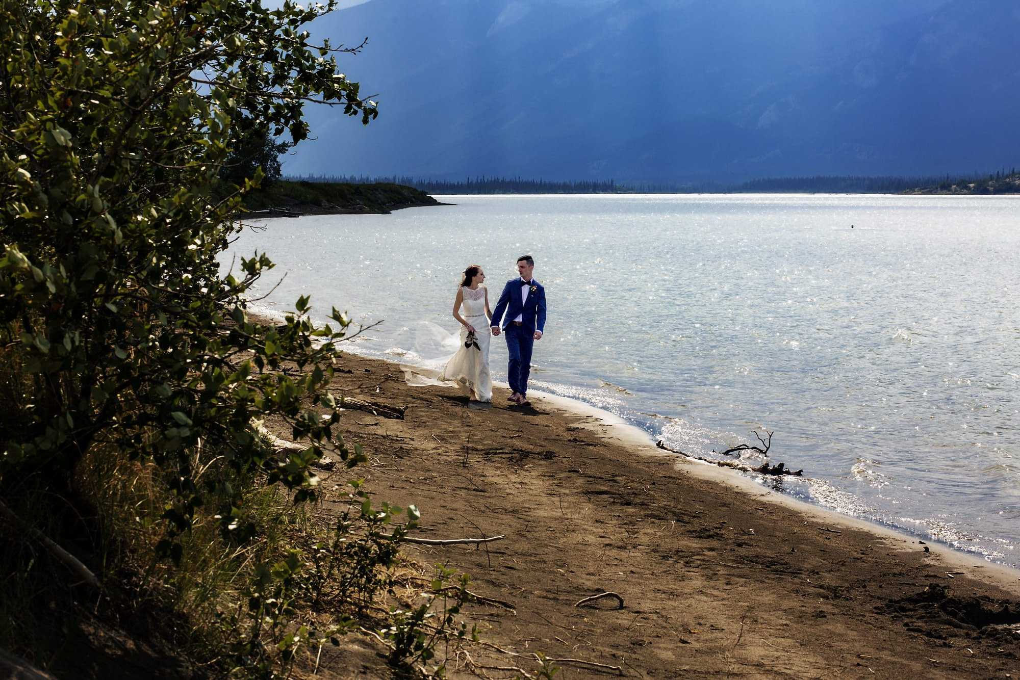 Wedding couple walking along Jasper Lake