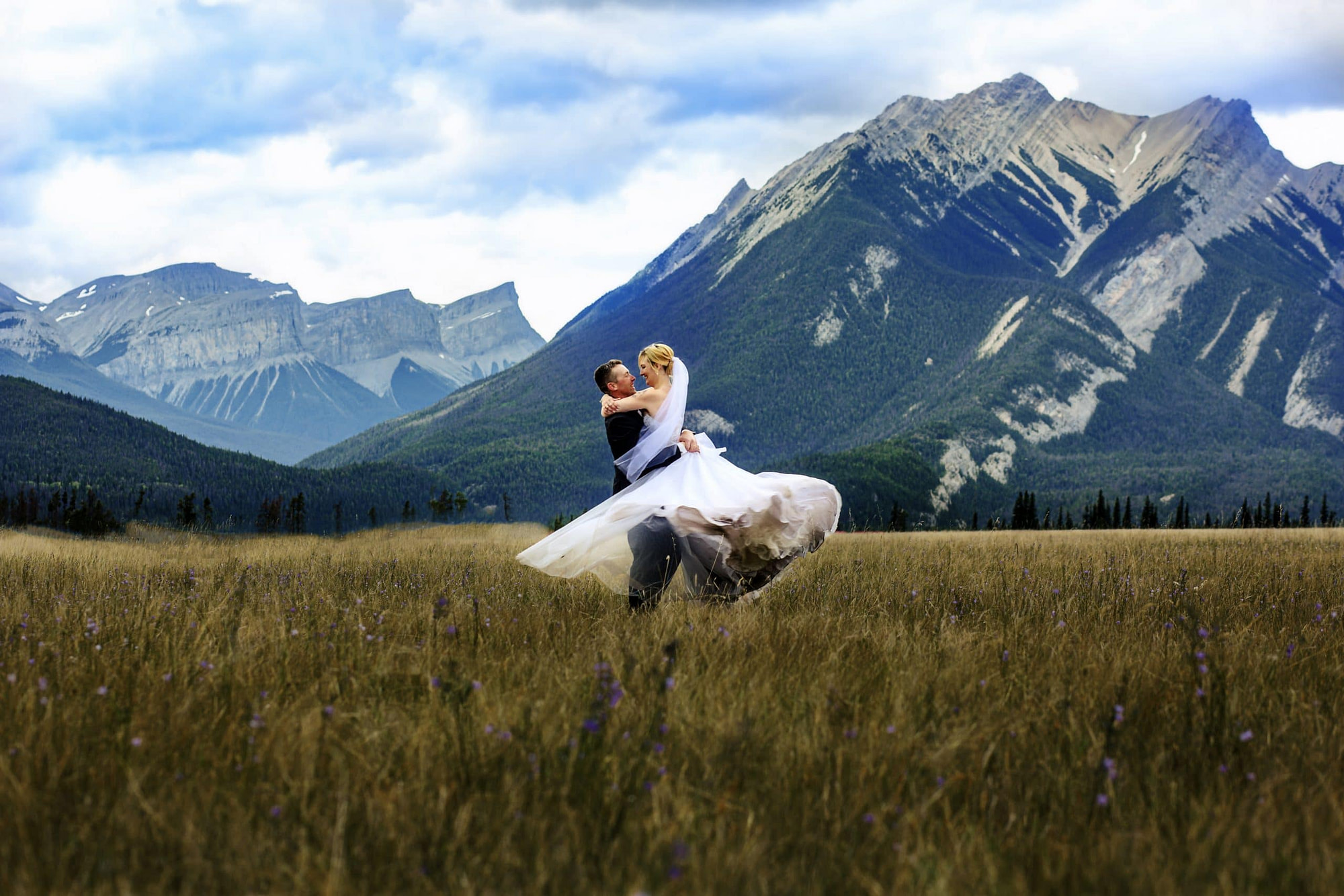 groom lift and spinning bride around in a meadow