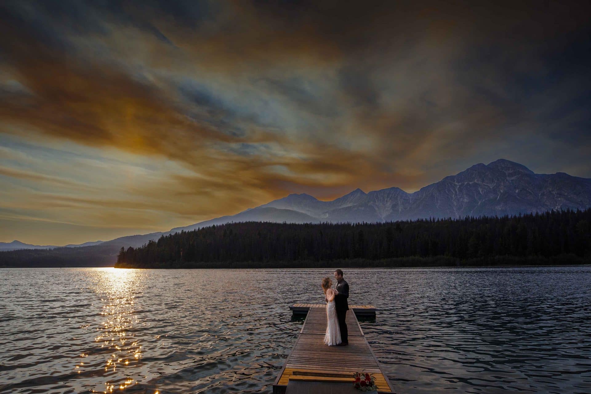bride and groom standing on the dock on Patricia Lake at sunset | Jasper photographers
