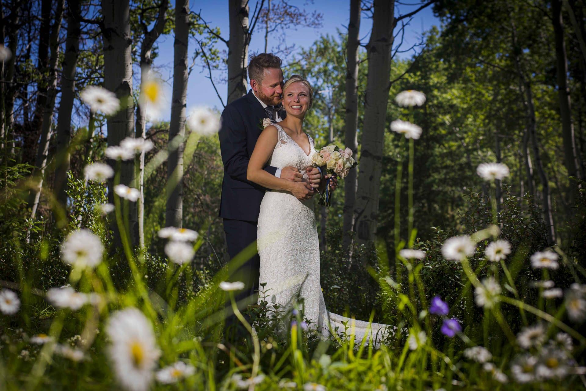 bride and groom cuddling in close in amongst wild flowers in Jasper | Jasper photographers