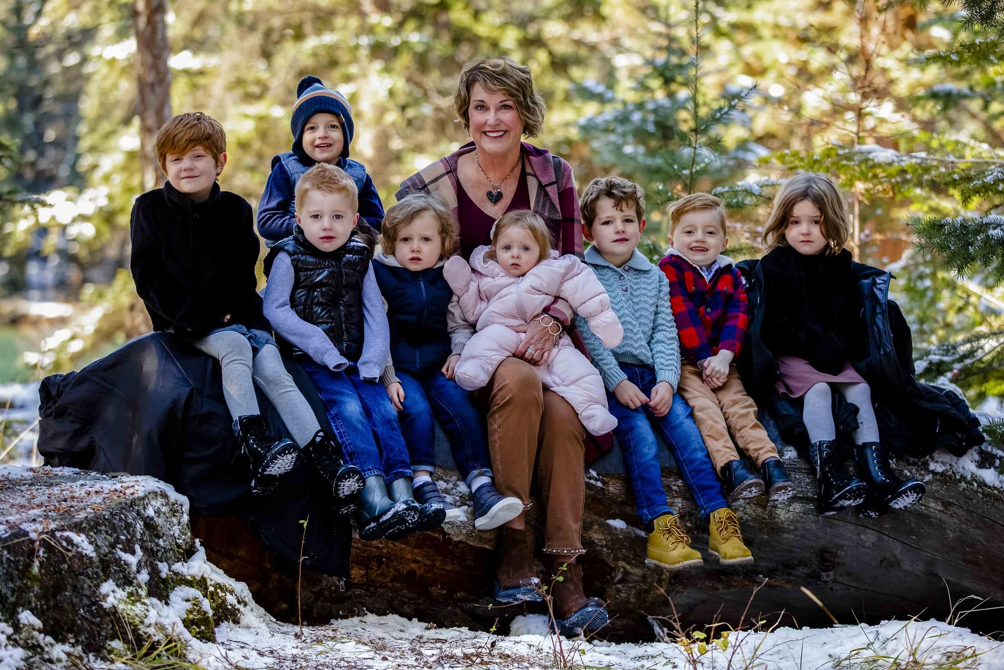 woman with 8 small children sitting on a log at Jasper Park Lodge | Jasper family photographers