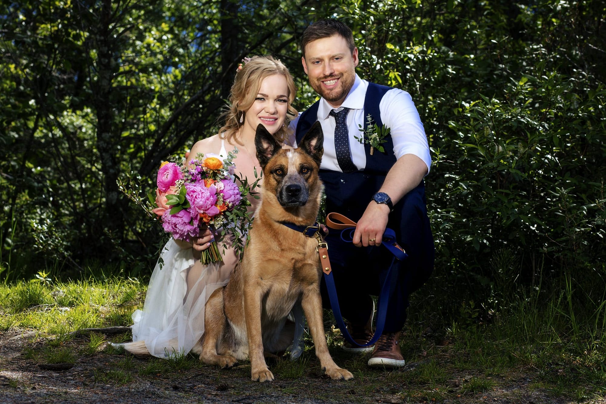 wedding couple crouching down and posing with dog in the centre- getting married in Jasper
