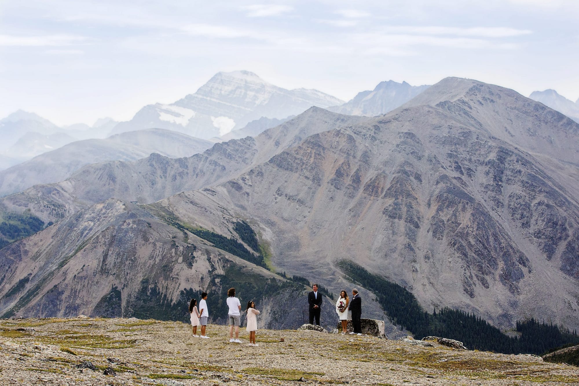 wedding ceremony in front of large mountains- Elope in Jasper