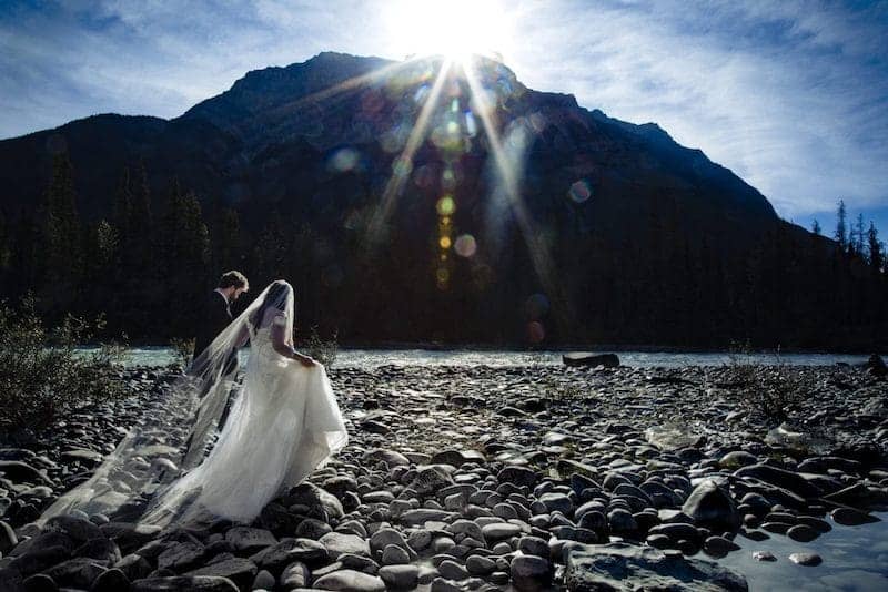 wedding couple walking next to Athabasca river in Jasper